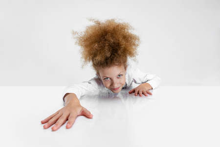 Close-up portrait of beautiful school girl sitting and looking at camera isolated on white background.の写真素材