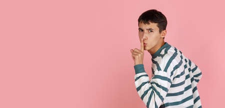 Portrait of young man, student or boy in casual clothes isolated on pink studio backgroud. Human emotions concept.の写真素材