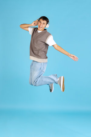 Portrait of young man, student or boy in casual clothes isolated on blue studio backgroud. Human emotions concept.の写真素材