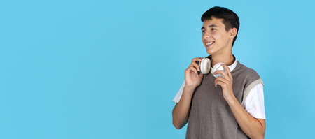 Portrait of young man, student or boy in casual clothes isolated on blue studio backgroud. Human emotions concept.の写真素材