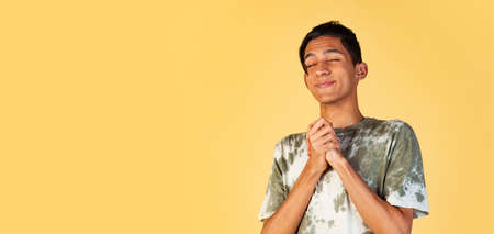 One young cute boy, teen, student in casual clothes smiling isolated on yellow studio backgroud. Human emotions concept.の写真素材