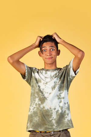 Portrait of young handsome boy, student in casual clothes posing isolated on yellow studio...