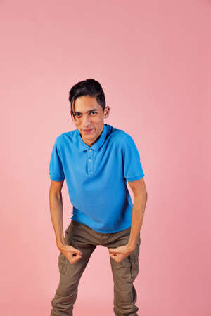 Portrait of young teen boy, student wearing blue shirt posing isolated on pink studio backgroud. Human emotions concept.の写真素材