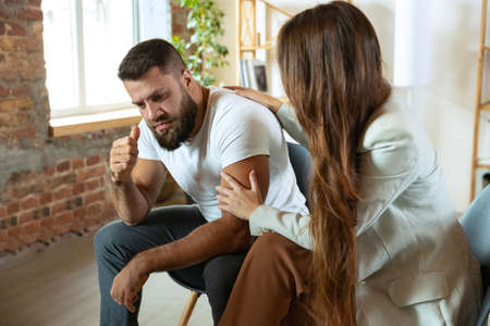 Two young people, married couple sitting in psychologists office. Look depressed, angry. despairedの写真素材