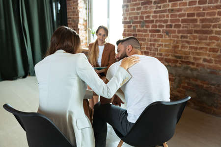 Back view of married couple, man and woman meeting with female consultant, psychologist to solve problemの写真素材