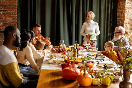 Happy Thanksgiving dinner party with family and friends with turkey and holiday traditional food, dishes on table.の写真素材