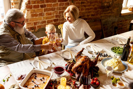 Happy grandfather, grandmother and grandson celebrate Thanksgiving day at home, indoors.の写真素材