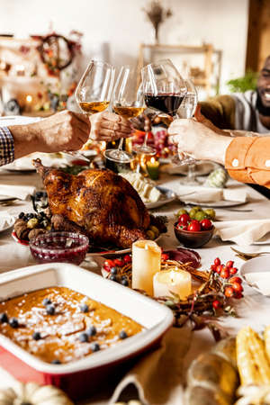 Close-up happy multiethnic big family celebrate Thanksgiving day, sitting at table with roasted turkey and holiday traditional food, dishes.の写真素材