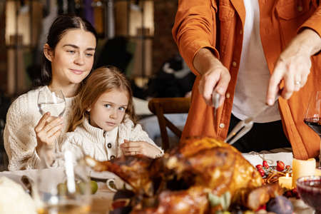 Close-up happy young men and women, married couple celebrate Thanksgiving day. Family dinner with roasted turkeyの写真素材