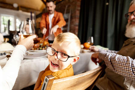 Close-up happy little boy looking at camera and smiling. Family Thanksgiving dinner with roasted turkeyの写真素材