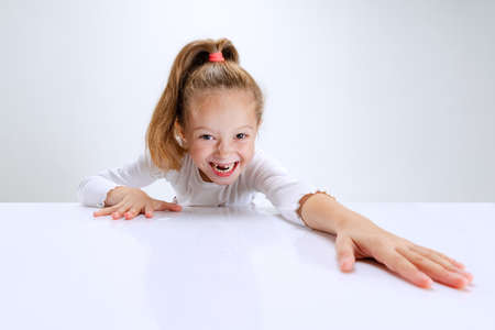 Portrait of beuatiful school girl sitting and looking at camera isolated on white background. Happy childhood, educationの写真素材