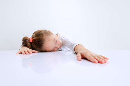 Portrait of beuatiful school girl sitting and looking at camera isolated on white background. Happy childhood, educationの写真素材