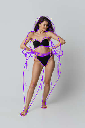One young beautiful slim woman in lingerie isolated over gray background. Line art. Modern artwork. Healthy eating conceptの写真素材