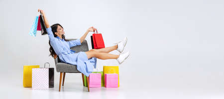 Happy beautiful young girl after shopping at black friday sales. Model with lots of bags, colorful bright packages isolated over white studio background.の写真素材