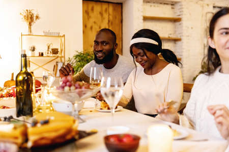 Happy Thanksgiving dinner party with family and friends with turkey and holiday traditional food, dishes on table.の写真素材