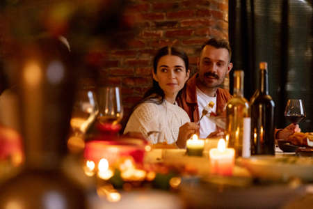 Close-up happy multiethnic big family celebrate Thanksgiving day, sitting at table with roasted turkey and holiday traditional food, dishes.の写真素材