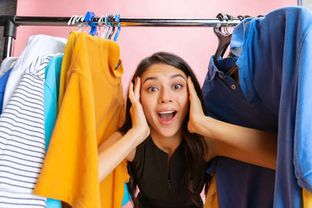 Beautiful young girl chooses clothes, outfit, dress in clothing store. Wow emotions, black friday, cyber monday, purchases, discount, ad.の写真素材