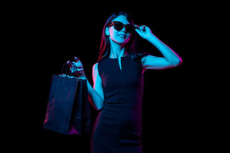Portrait of young woman in neon light on dark backgound. Human emotions, black friday, cyber monday, purchases, sales, finance concept.の写真素材