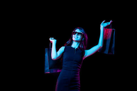 Portrait of young woman in neon light on dark backgound. Human emotions, black friday, cyber monday, purchases, sales, finance concept.の写真素材