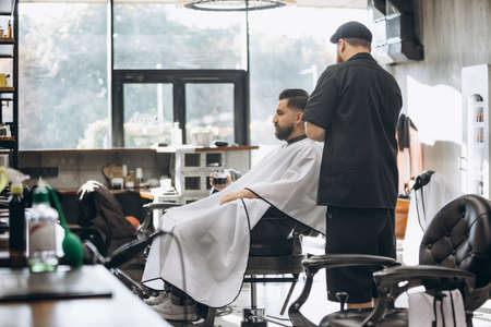 Man getting haircut at the barbershop. Professional barber at work process. Beauty, selfcare, style, fashion, healthcare and male cosmetics concept.の写真素材