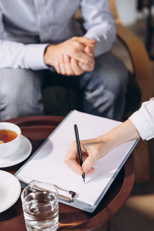 Close-up female hands writting down information. Meeting with psychologist. Concept of help, care, supportの写真素材