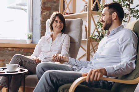 Meeting with psychologist. Happy married couple, young man and woman talking with consultant about lifeの写真素材