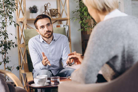 At a psychologists appointment. Married couple, sad, depressed man and woman meeting with consultant to solve family problemの写真素材