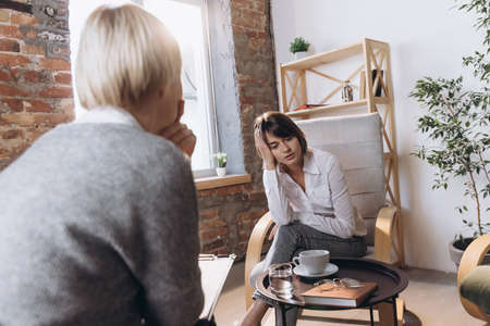 Two young women, patient and doctor discussing psychological problems at meeting with psychologist.の写真素材