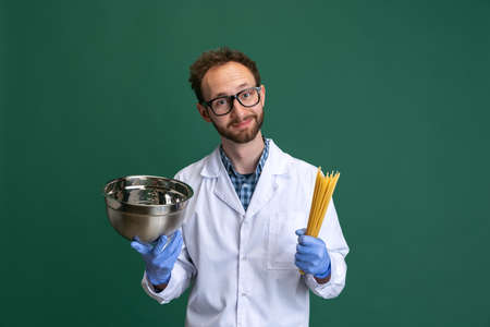 Comic portrait of young man wearing white gown and protective gloves having fun isolated on green background.の写真素材