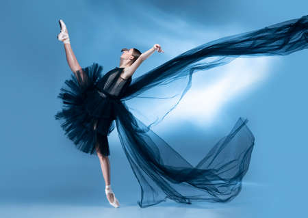 Young and graceful ballet dancer in black stage outfit, dress isolated on white blue studio background in neon light.の写真素材