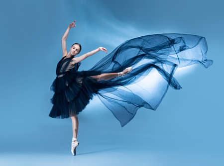 Young and graceful ballet dancer in black stage outfit, dress isolated on white blue studio background in neon light.の写真素材
