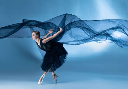 Young and graceful ballet dancer in black stage outfit, dress isolated on white blue studio background in neon light.の写真素材