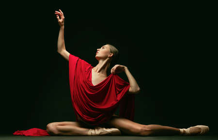 Graceful classic ballerina posing like greek goddess isolated on dark studio background. Grace, art, performance concept.の写真素材