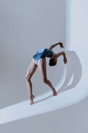 Young and graceful ballet dancer, ballerina dancing isolated on light studio background. Art, motion, action, flexibility, inspiration concept.の写真素材