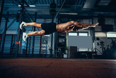 Portrait of muscled athlete, bodybuilder workouts alone at sport gym, indoors. Concept of sport,...