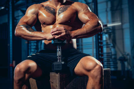 Close-up male muscled body, bodybuilder posing at sport gym, indoors. Concept of sport, activity,...