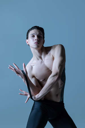 Portrait of young man, flexible male ballet dancer dancing isolated on old navy studio background....