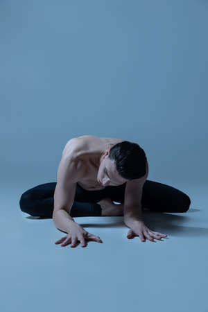 Young and graceful male ballet dancer in art performance isolated on old navy studio background. Art, motion, action, flexibility, inspiration concept.の写真素材