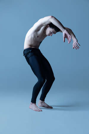 Portrait of young man, flexible male ballet dancer dancing isolated on old navy studio background. Art, motion, inspiration concept.の写真素材