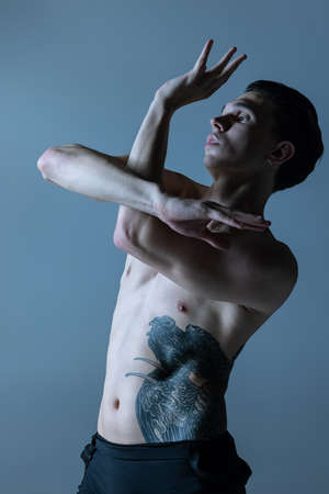 Half-length portrait of young man, flexible male contemp dancer dancing isolated on old navy studio background. Art, motion, inspiration concept.の写真素材