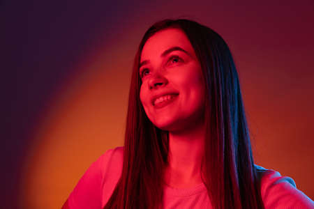 Charming happy girl isolated on dark studio background in neon light. Concept of human emotions,...