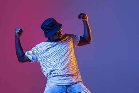 Winning success happy man celebrating being a winner. Dynamic image of male model on gradient purple pink studio background in neonの写真素材