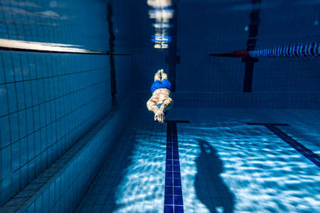 Underwater shooting. One male swimmer training at pool, indoors. Underwater view of swimming movements details.の写真素材