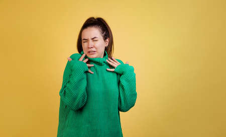 Half-lenght portrait of young cute girl, student wearing green sweater posing isolated on yellow studio background. Concept of emotions, fashionの写真素材