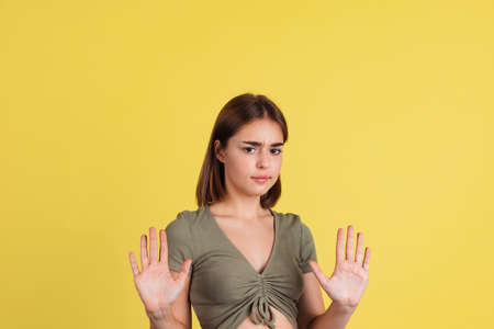 Half-length portrait of young beautiful girl, student in brown tee isolated on yellow studio...