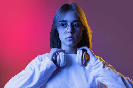 Studio shot of young serious girl, student in casual wear states at gaze isolated on pink-purple...