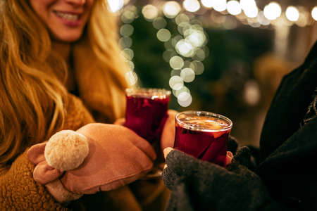 Close-up womans hands in winter mittens with hot cup of hot mulled wine. Holidays, traditions, winter fair, Christmas conceptの写真素材