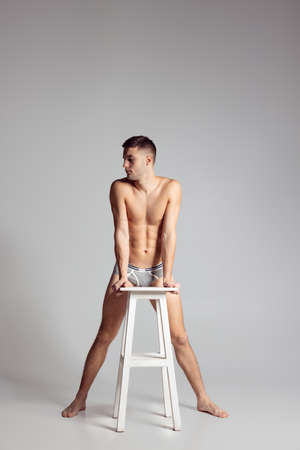 Studio shot of young handsome sportive shirtless man in underwear standing isolated on grey studio background.の写真素材