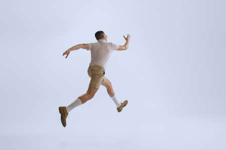 Dynamic portrait of young man dressed in 50s, 60s style running away isolated on white background. Retro vintage styleの写真素材