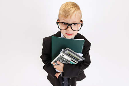 High angle view of cute little boy, kid businessman in huge suit jacket wearing eyeglasses isolated on white studio background.の写真素材